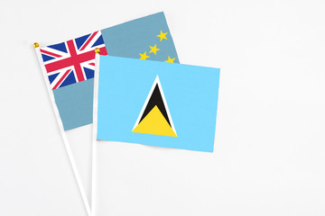 Saint Lucia and Tuvalu stick flags on white background. High quality fabric, miniature national flag. Peaceful global concept.White floor for copy space.