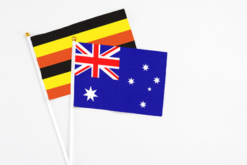 Fototapeta premium Australia and Uganda stick flags on white background. High quality fabric, miniature national flag. Peaceful global concept.White floor for copy space.