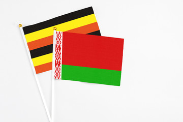 Belarus and Uganda stick flags on white background. High quality fabric, miniature national flag. Peaceful global concept.White floor for copy space.