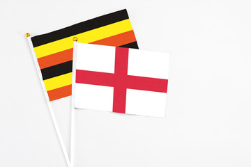 England and Uganda stick flags on white background. High quality fabric, miniature national flag. Peaceful global concept.White floor for copy space.