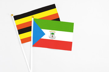 Equatorial Guinea and Uganda stick flags on white background. High quality fabric, miniature national flag. Peaceful global concept.White floor for copy space.