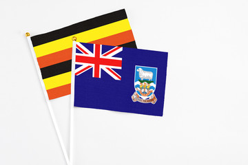 Falkland Islands and Uganda stick flags on white background. High quality fabric, miniature...