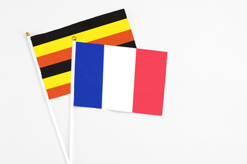 Fototapeta premium France and Uganda stick flags on white background. High quality fabric, miniature national flag. Peaceful global concept.White floor for copy space.