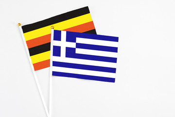 Greece and Uganda stick flags on white background. High quality fabric, miniature national flag. Peaceful global concept.White floor for copy space.