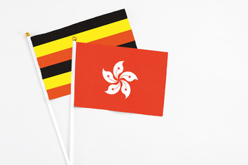 Hong Kong and Uganda stick flags on white background. High quality fabric, miniature national flag. Peaceful global concept.White floor for copy space.