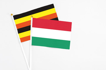Hungary and Uganda stick flags on white background. High quality fabric, miniature national flag. Peaceful global concept.White floor for copy space.