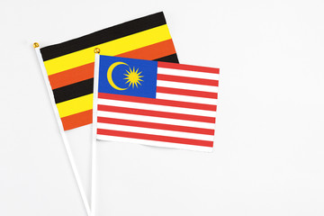 Malaysia and Uganda stick flags on white background. High quality fabric, miniature national flag. Peaceful global concept.White floor for copy space.
