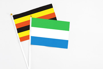 Sierra Leone and Uganda stick flags on white background. High quality fabric, miniature national flag. Peaceful global concept.White floor for copy space.