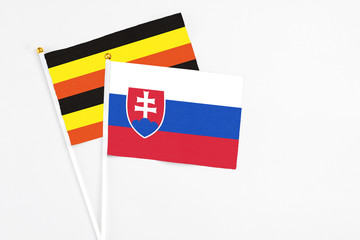 Slovakia and Uganda stick flags on white background. High quality fabric, miniature national flag. Peaceful global concept.White floor for copy space.