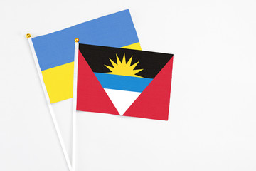 Antigua and Barbuda and Ukraine stick flags on white background. High quality fabric, miniature national flag. Peaceful global concept.White floor for copy space.