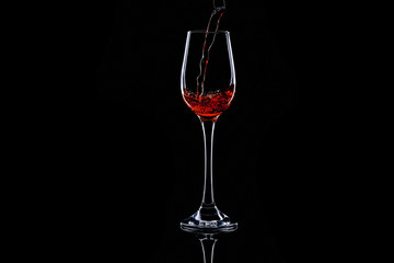 pouring red wine in glass on dark background. Isolated silhouette