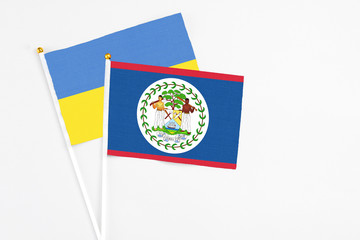 Belize and Ukraine stick flags on white background. High quality fabric, miniature national flag. Peaceful global concept.White floor for copy space.