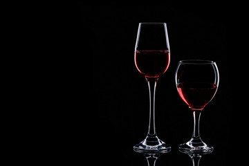 Naklejka na ściany i meble Two glasses silhouette with red wine isolated on black background