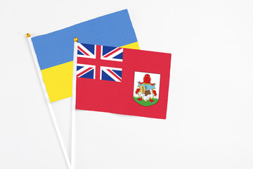 Fototapeta premium Bermuda and Ukraine stick flags on white background. High quality fabric, miniature national flag. Peaceful global concept.White floor for copy space.