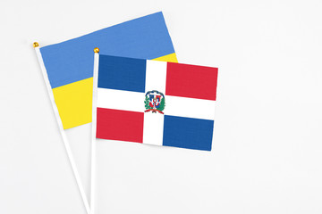 Dominican Republic and Ukraine stick flags on white background. High quality fabric, miniature national flag. Peaceful global concept.White floor for copy space.