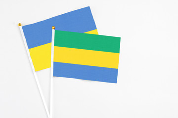 Gabon and Ukraine stick flags on white background. High quality fabric, miniature national flag. Peaceful global concept.White floor for copy space.