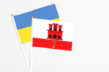 Gibraltar and Ukraine stick flags on white background. High quality fabric, miniature national flag. Peaceful global concept.White floor for copy space.