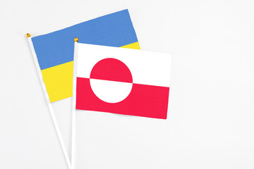 Greenland and Ukraine stick flags on white background. High quality fabric, miniature national flag. Peaceful global concept.White floor for copy space.