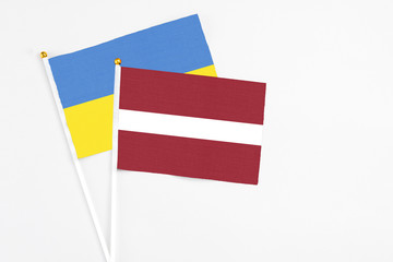 Latvia and Ukraine stick flags on white background. High quality fabric, miniature national flag. Peaceful global concept.White floor for copy space.