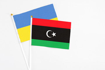 Libya and Ukraine stick flags on white background. High quality fabric, miniature national flag. Peaceful global concept.White floor for copy space.