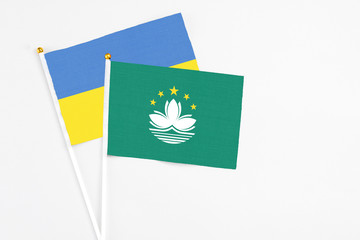 Macao and Ukraine stick flags on white background. High quality fabric, miniature national flag. Peaceful global concept.White floor for copy space.