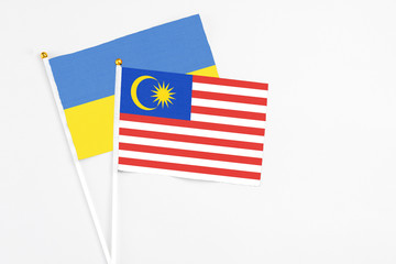 Malaysia and Ukraine stick flags on white background. High quality fabric, miniature national flag. Peaceful global concept.White floor for copy space.