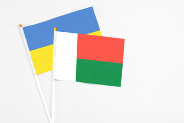 Madagascar and Ukraine stick flags on white background. High quality fabric, miniature national flag. Peaceful global concept.White floor for copy space.