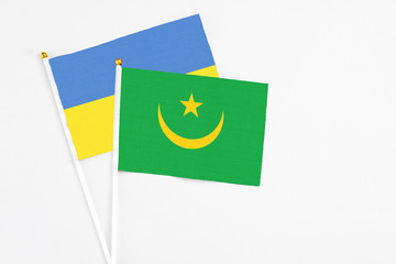Mauritania and Ukraine stick flags on white background. High quality fabric, miniature national flag. Peaceful global concept.White floor for copy space.