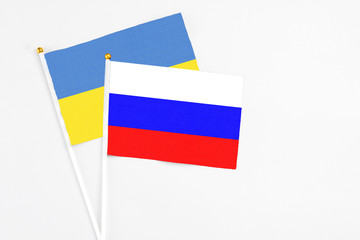 Russia and Ukraine stick flags on white background. High quality fabric, miniature national flag. Peaceful global concept.White floor for copy space.