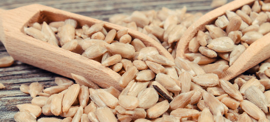 Sunflower with wooden spoons. Healthy food as source minerals and fiber. Wooden background