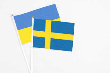 Sweden and Ukraine stick flags on white background. High quality fabric, miniature national flag. Peaceful global concept.White floor for copy space.