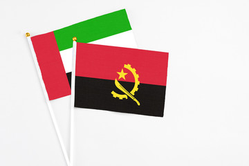 Angola and United Arab Emirates stick flags on white background. High quality fabric, miniature national flag. Peaceful global concept.White floor for copy space.