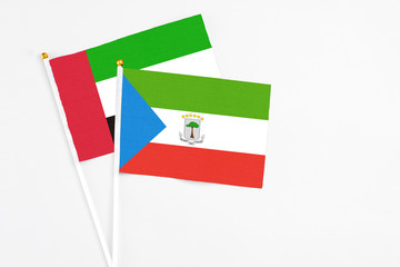 Equatorial Guinea and United Arab Emirates stick flags on white background. High quality fabric, miniature national flag. Peaceful global concept.White floor for copy space.