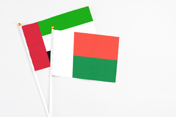 Madagascar and United Arab Emirates stick flags on white background. High quality fabric, miniature national flag. Peaceful global concept.White floor for copy space.