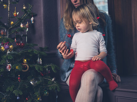 Mother and toddler with heart shaped lights by christmas tree