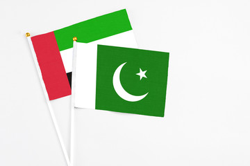 Pakistan and United Arab Emirates stick flags on white background. High quality fabric, miniature national flag. Peaceful global concept.White floor for copy space.