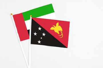 Papua New Guinea and United Arab Emirates stick flags on white background. High quality fabric, miniature national flag. Peaceful global concept.White floor for copy space.