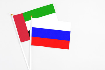 Russia and United Arab Emirates stick flags on white background. High quality fabric, miniature national flag. Peaceful global concept.White floor for copy space.
