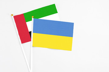 Ukraine and United Arab Emirates stick flags on white background. High quality fabric, miniature national flag. Peaceful global concept.White floor for copy space.