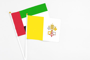 Vatican City and United Arab Emirates stick flags on white background. High quality fabric, miniature national flag. Peaceful global concept.White floor for copy space.