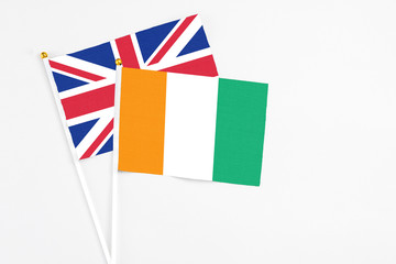 Cote D'Ivoire and United Kingdom stick flags on white background. High quality fabric, miniature national flag. Peaceful global concept.White floor for copy space.