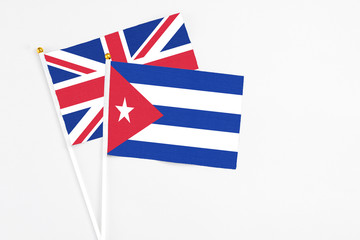 Cuba and United Kingdom stick flags on white background. High quality fabric, miniature national flag. Peaceful global concept.White floor for copy space.