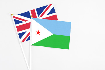 Fototapeta na wymiar Djibouti and United Kingdom stick flags on white background. High quality fabric, miniature national flag. Peaceful global concept.White floor for copy space.