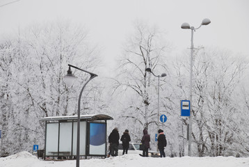 people waiting for a bus at a stop on a frosty winter day