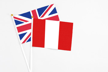 Fototapeta na wymiar Peru and United Kingdom stick flags on white background. High quality fabric, miniature national flag. Peaceful global concept.White floor for copy space.