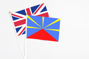 Reunion and United Kingdom stick flags on white background. High quality fabric, miniature national flag. Peaceful global concept.White floor for copy space.