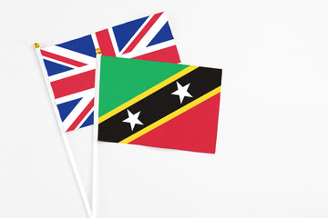 Fototapeta premium Saint Kitts And Nevis and United Kingdom stick flags on white background. High quality fabric, miniature national flag. Peaceful global concept.White floor for copy space.