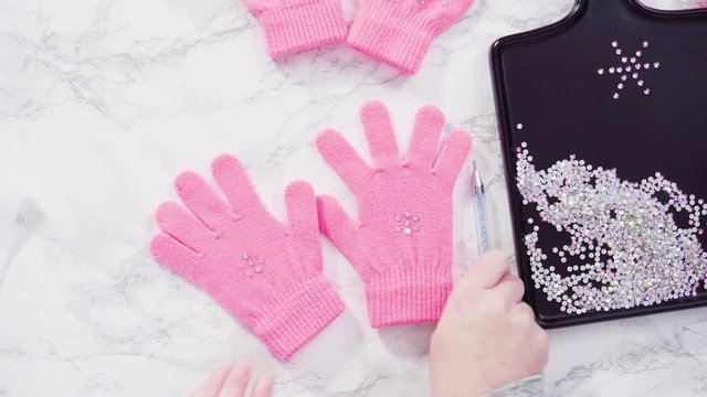 Flat lay. Rhinestone pink kids gloves with snowflake shapes.