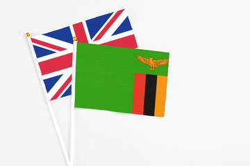 Zambia and United Kingdom stick flags on white background. High quality fabric, miniature national flag. Peaceful global concept.White floor for copy space.