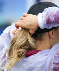 The blonde girl collects hair on her head under a cap